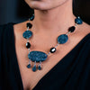 Woman wearing a fashion statement necklace made of clay, onyx, and spinel.