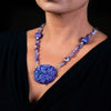 Woman wearing a fashion statement necklace made of clay, amethyst, and sterling silver beads. 