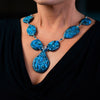 Woman wearing a fashion statement necklace made of clay and chrysocolla.