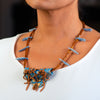 woman wearing handmade necklace made of clay, coral, and kyanite.