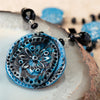 Pendant from a fashion statement necklace made of blue and black clay with a flower imprint.