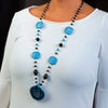 Woman wearing a fashion statement necklace made of clay, onyx, glass beads and dumortierite.