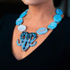 Woman wearing a fashion statement necklace made of clay, blue lace agate, and spinel.